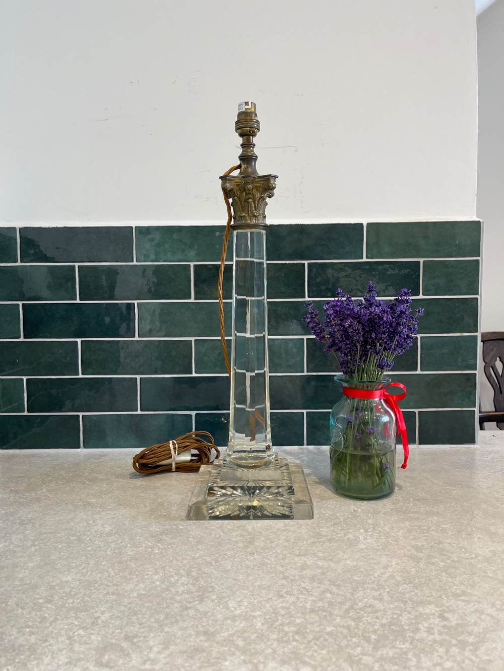 A 19th-century clear cut glass table lamp featuring a brass Corinthian capital mount and a stepped square base.