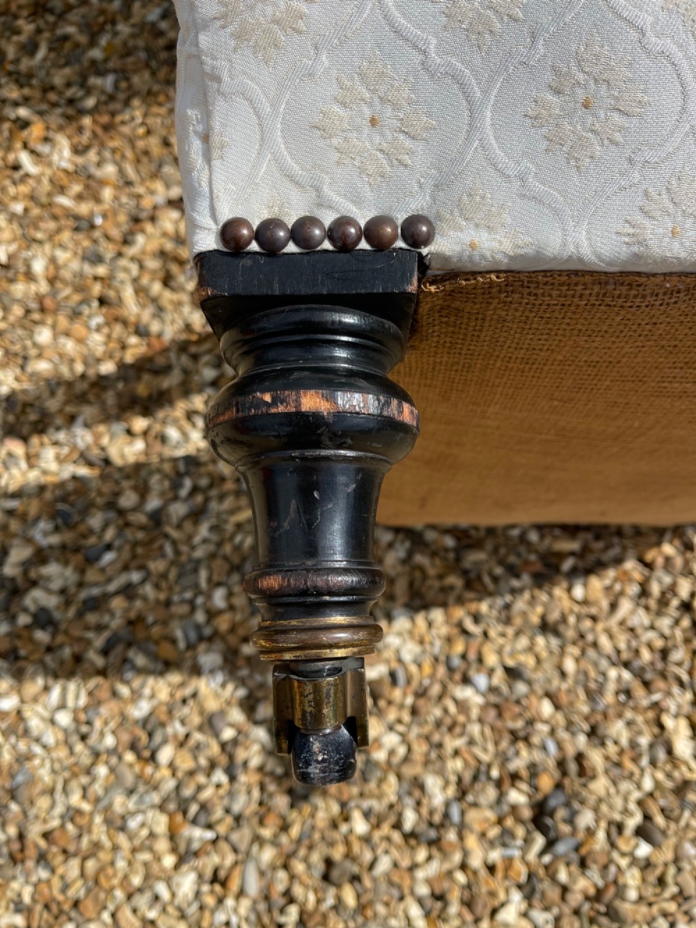 A Victorian open armchair upholstered in cream damask pattern fabric featuring turned dark wood arm supports and front legs with castors. View IV