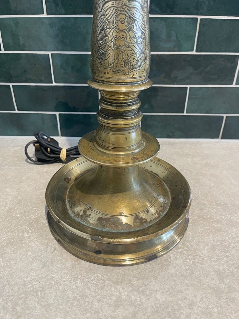 A tall, hand-engraved brass table lamp base featuring a tapered column, intricate etched figurative motifs, turned mouldings, and a stepped circular foot. View II