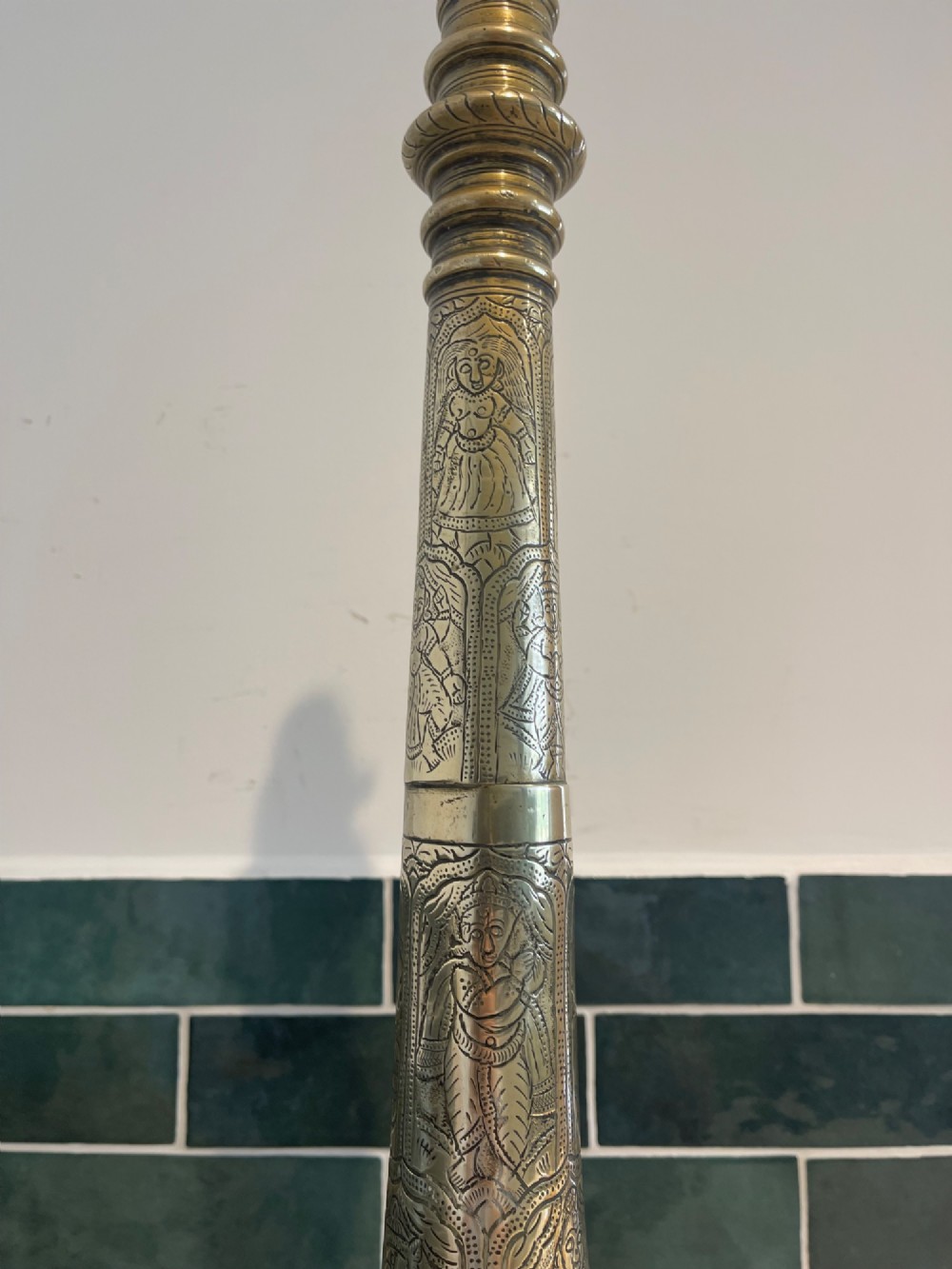 A tall, hand-engraved brass table lamp base featuring a tapered column, intricate etched figurative motifs, turned mouldings, and a stepped circular foot. View III