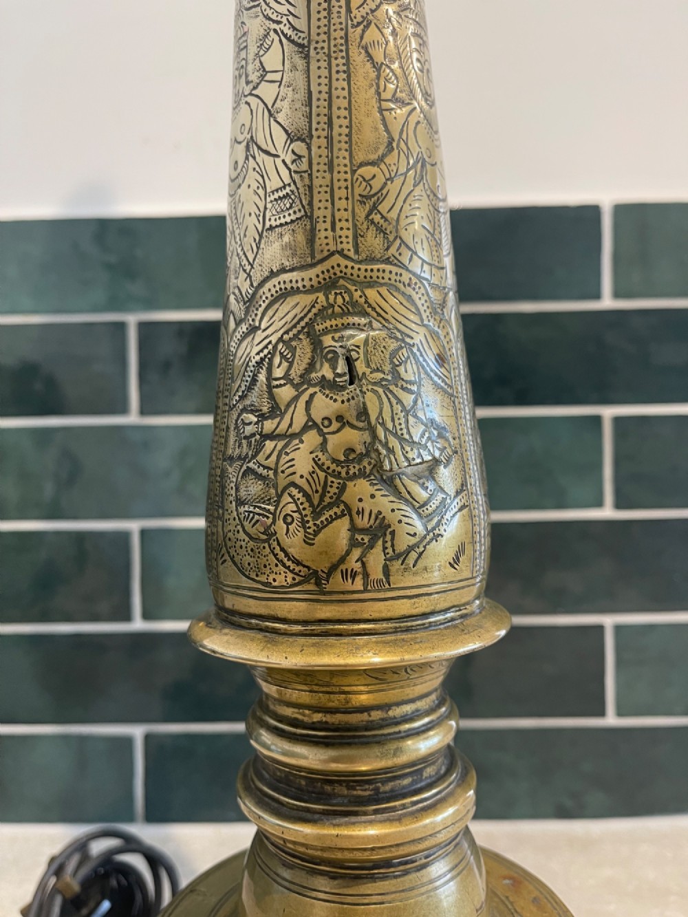A tall, hand-engraved brass table lamp base featuring a tapered column, intricate etched figurative motifs, turned mouldings, and a stepped circular foot. View IV