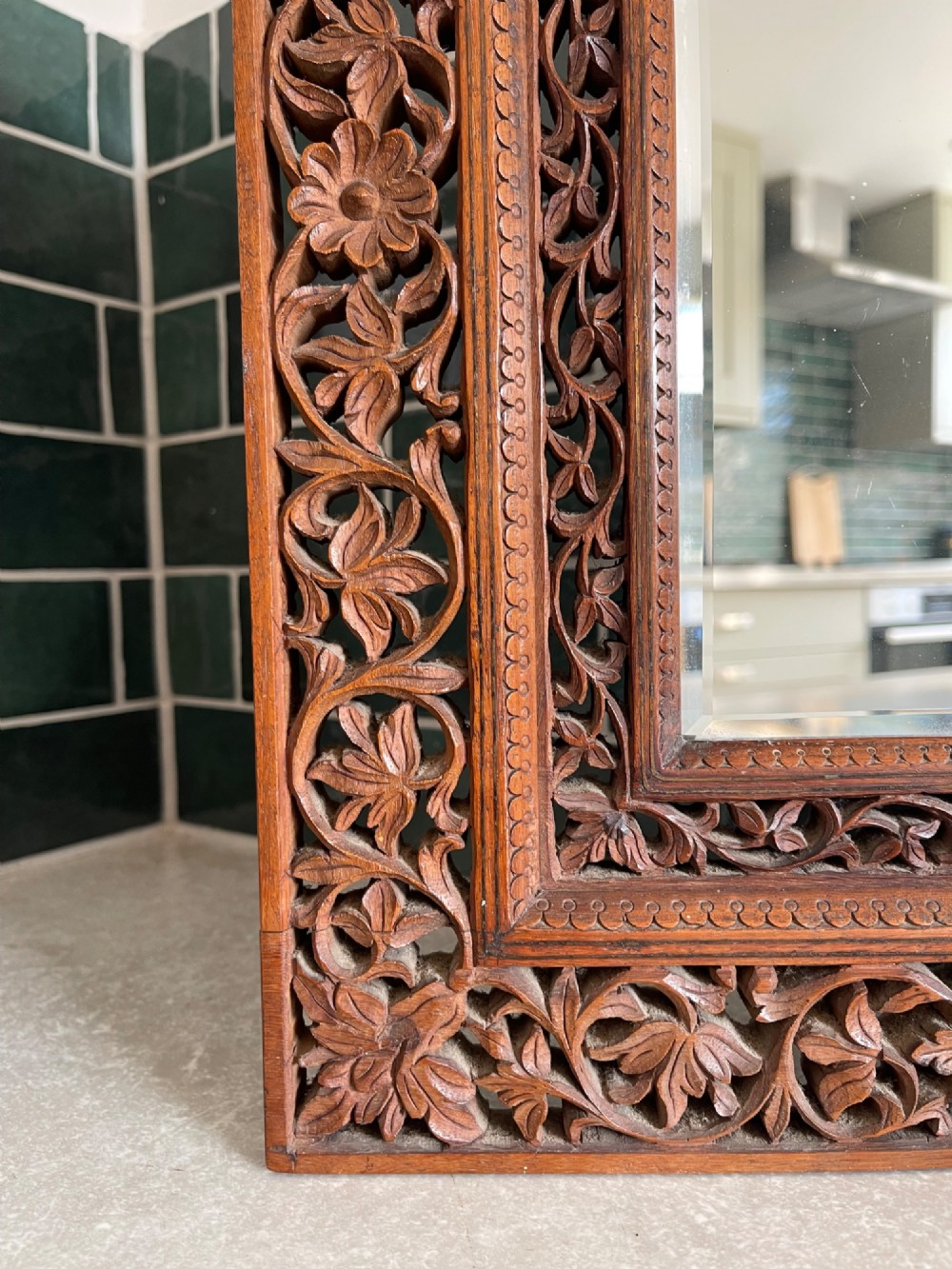 A rectangular wooden wall mirror featuring a deeply hand-carved openwork floral border surrounding a central bevelled glass pane. View II