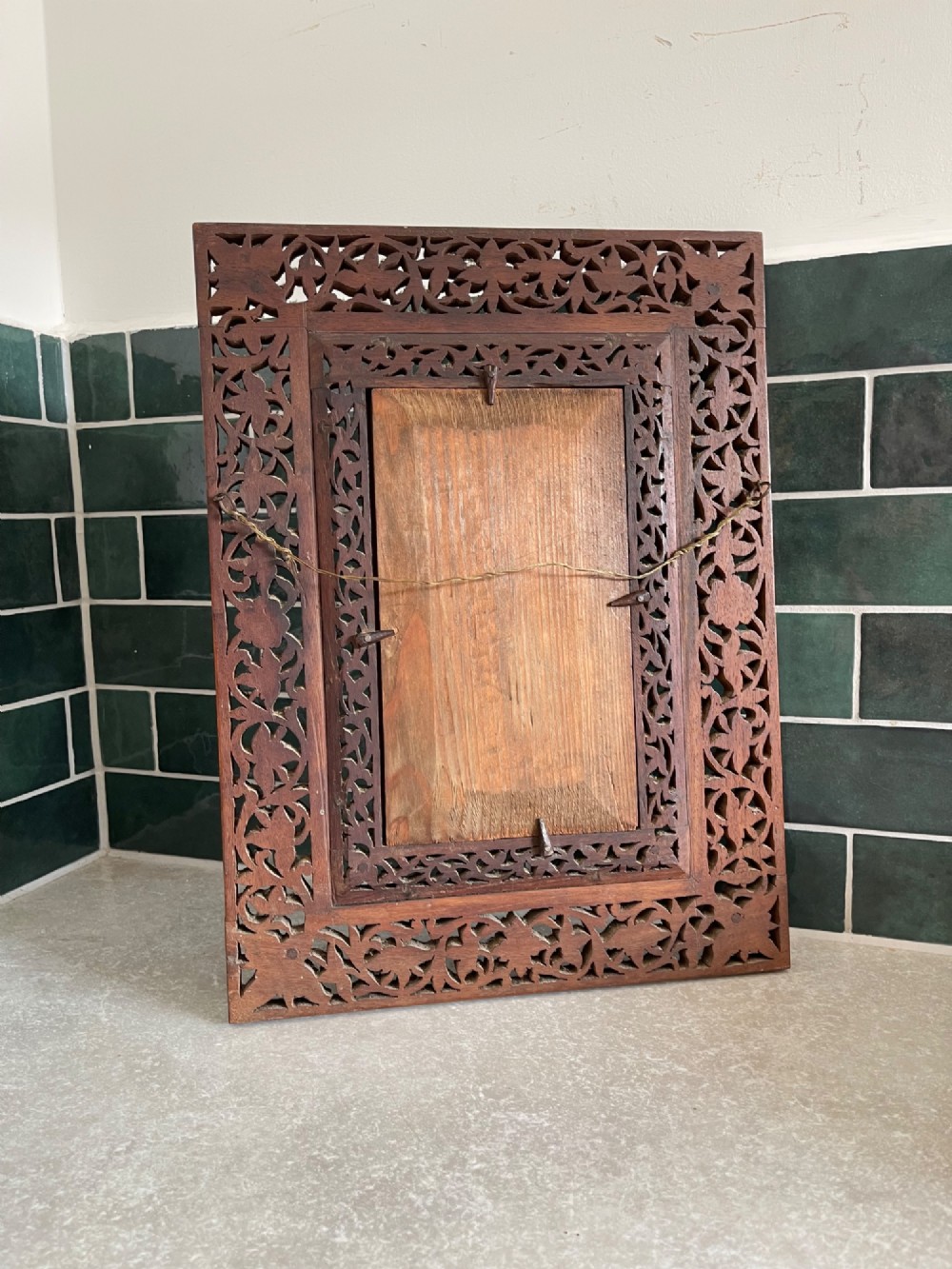 A rectangular wooden wall mirror featuring a deeply hand-carved openwork floral border surrounding a central bevelled glass pane. View III