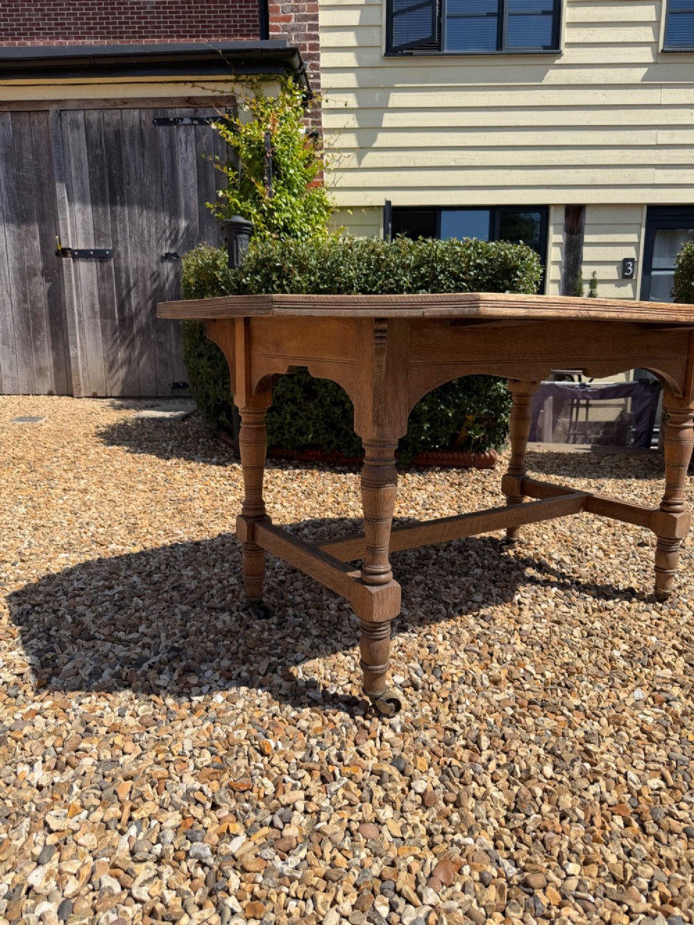 A nineteenth-century octagonal oak table featuring turned legs connected by stretchers and mounted on brass castors. View III