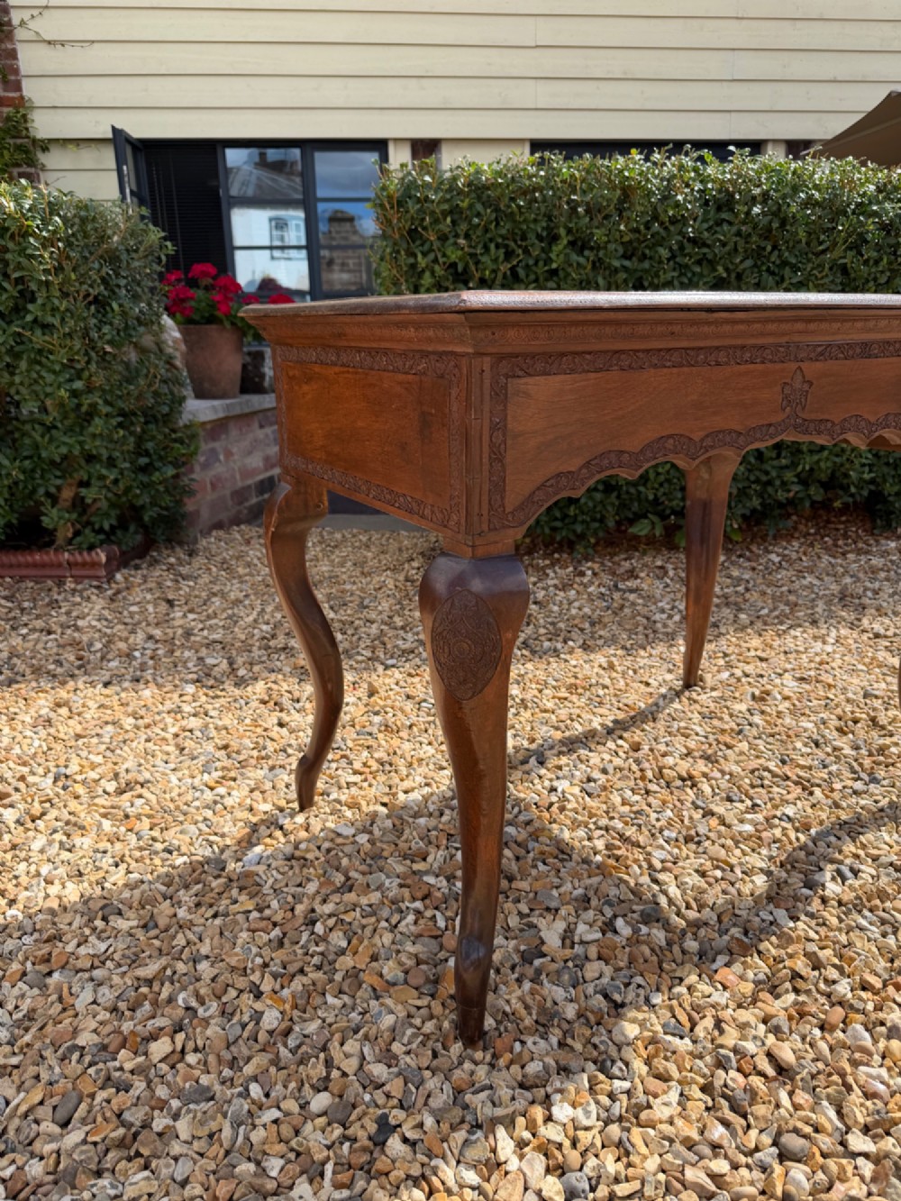 A rectangular hand-carved walnut table featuring slender cabriole legs, a scalloped apron, and relief carving along the top edge. View V