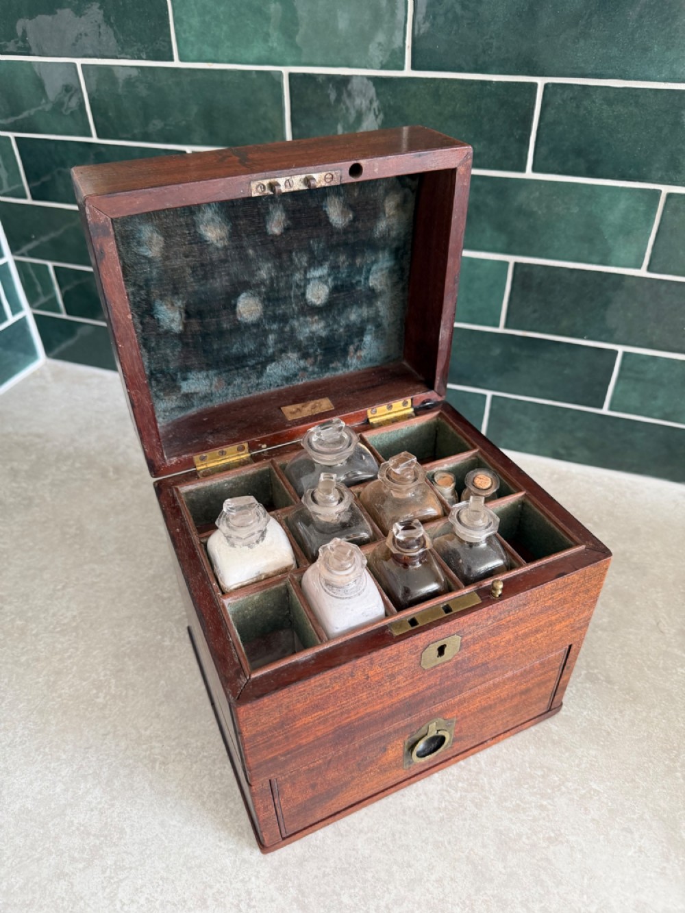 A rectangular 19th-century mahogany apothecary box featuring brass hardware, a flush top carrying handle, a keyhole, and a lower drawer. View II