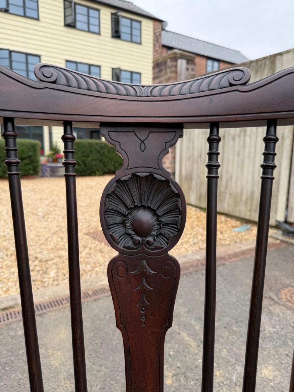 A carved dark mahogany armchair featuring cabriole front legs, turned spindles, a central shell back splat, and a shaped wooden seat. View VI