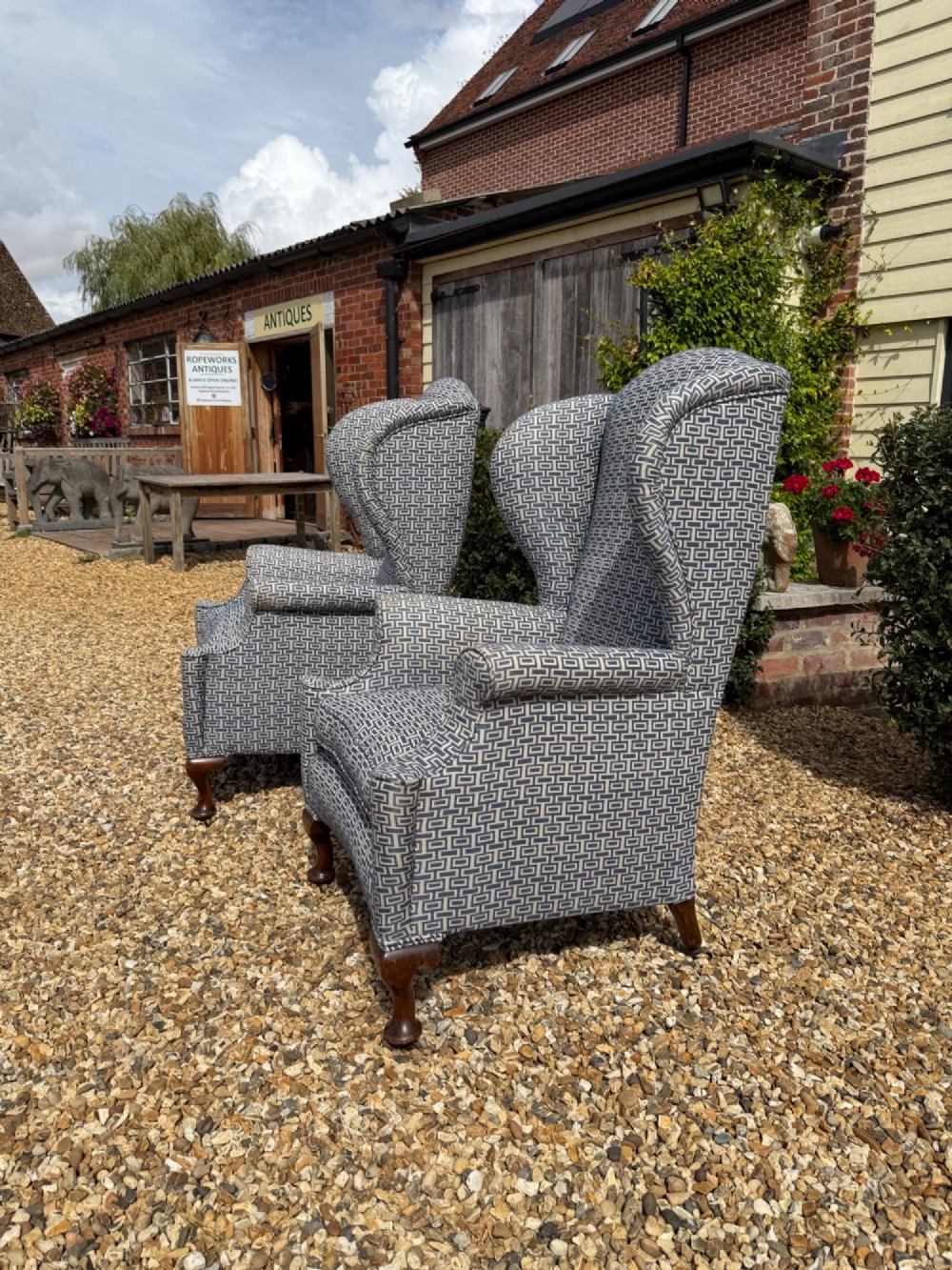 A pair of high-backed wingback armchairs upholstered in blue and grey geometric patterned fabric with carved dark timber cabriole legs. View III