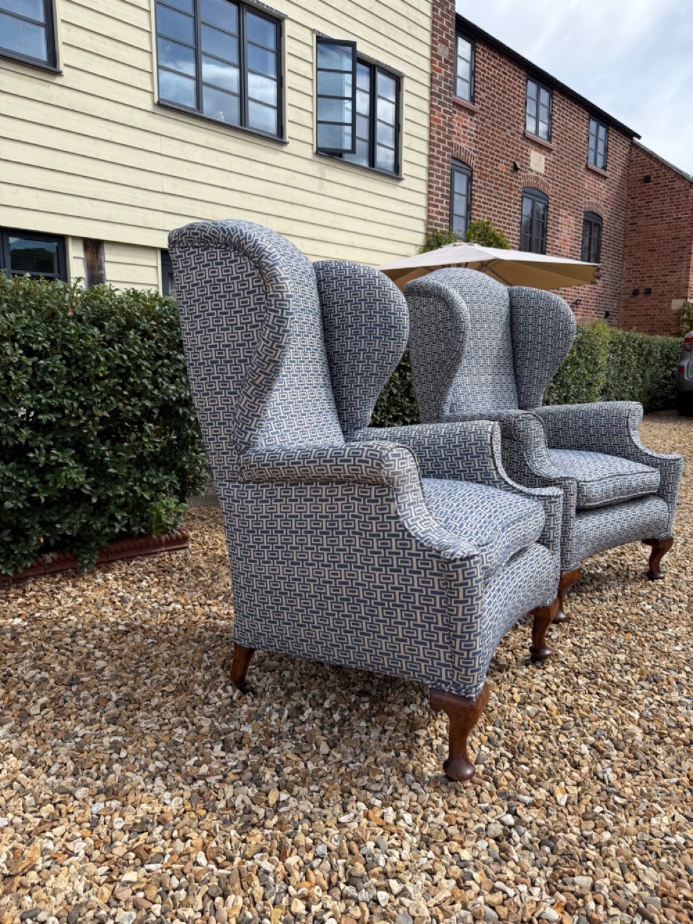 A pair of high-backed wingback armchairs upholstered in blue and grey geometric patterned fabric with carved dark timber cabriole legs. View IV