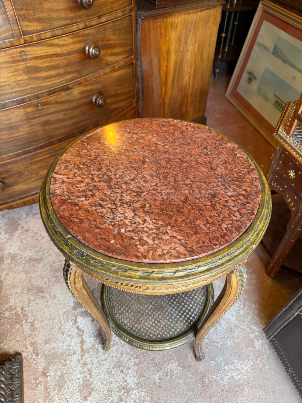 A nineteenth-century French circular gueridon table featuring a red marble top, carved giltwood frame, and lower caned tier. View III