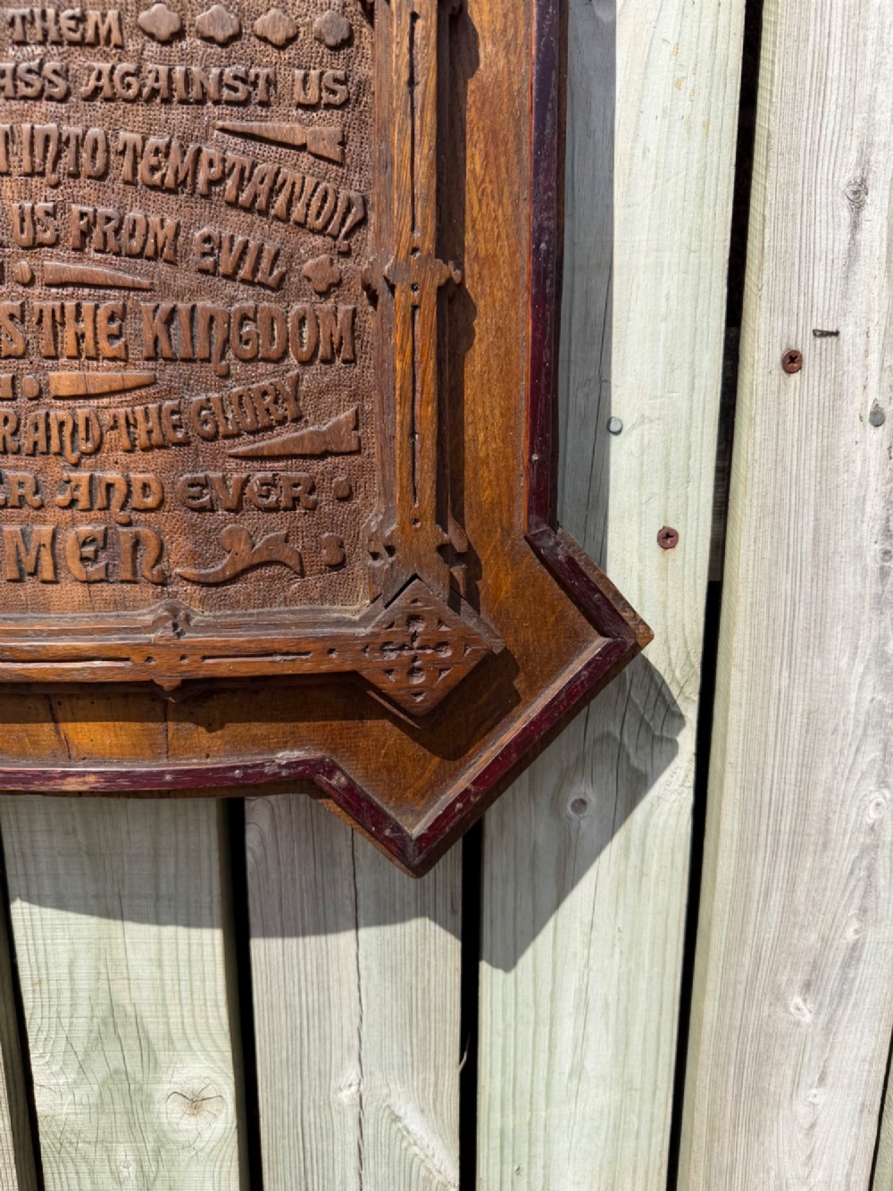 A vertical carved dark oak plaque shaped like a Gothic arch with a cross finial, featuring relief-carved lettering of the Lords Prayer. View II
