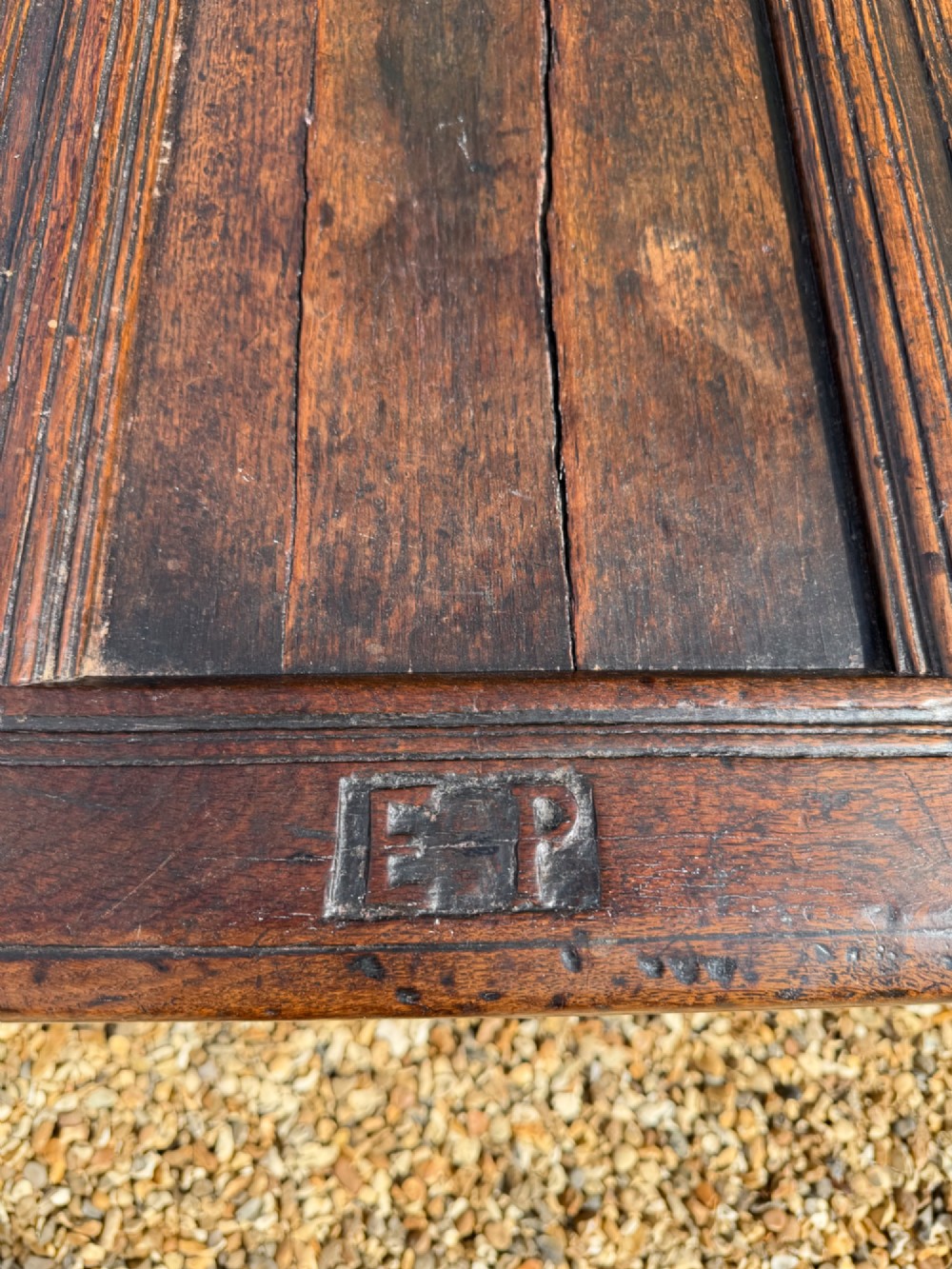 A 17th-century dark oak coffer featuring three carved panelled sections on the front, rosette border carvings, and peg joinery. View IV