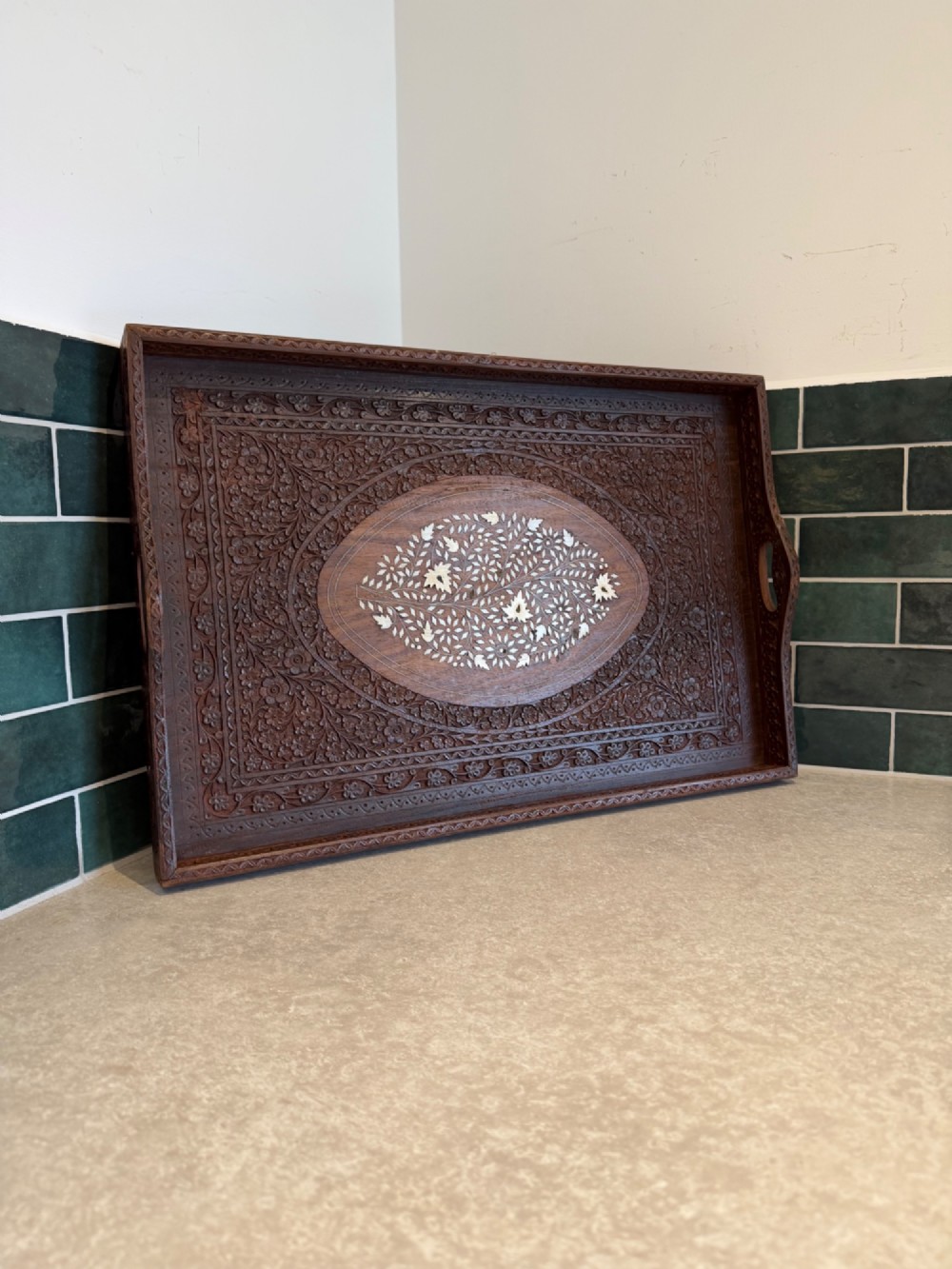 A rectangular dark walnut serving tray featuring intricate floral woodcarvings and a central oval medallion with delicate light-coloured inlay.