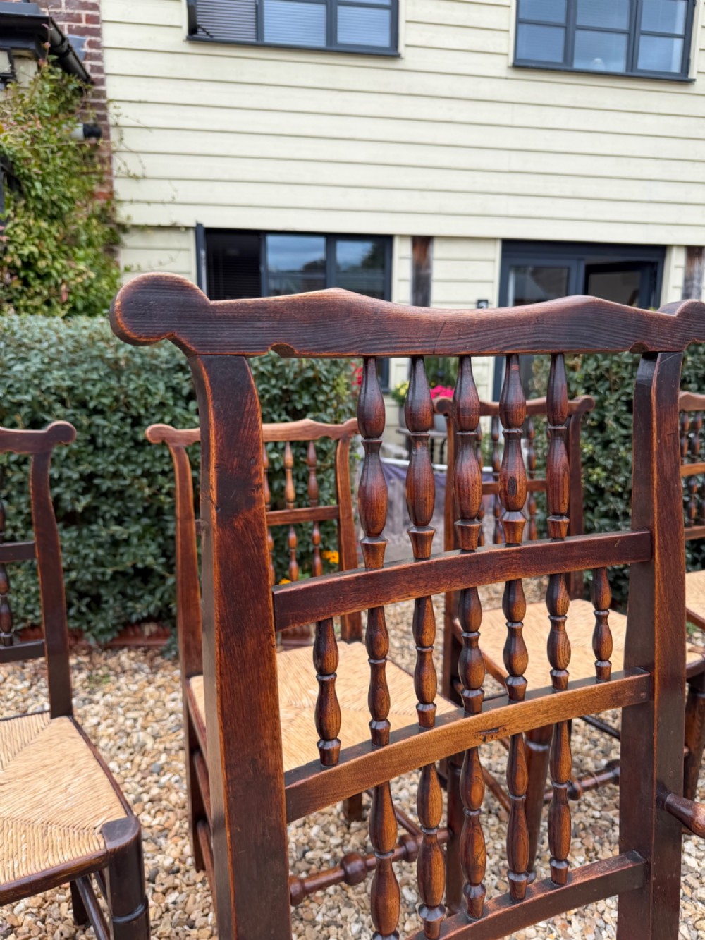 A set of eight dark wood dining chairs featuring spindle backs and woven rush seats, comprising two armchairs and six side chairs. View II