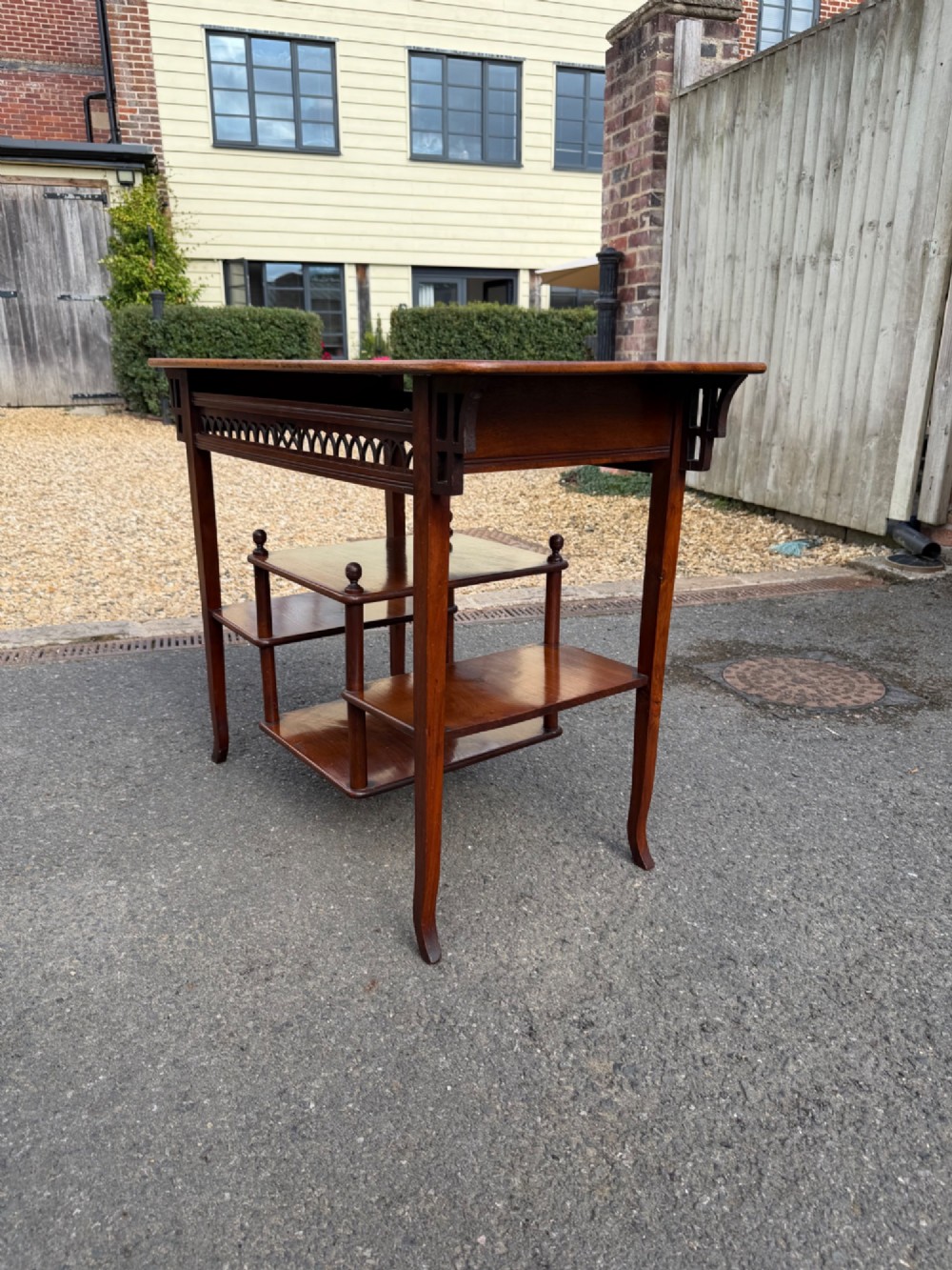 An Anglo-Japanese walnut occasional table featuring a rectangular top, an openwork fretwork frieze, and asymmetrical staggered lower shelves supported by turned spindles. View III