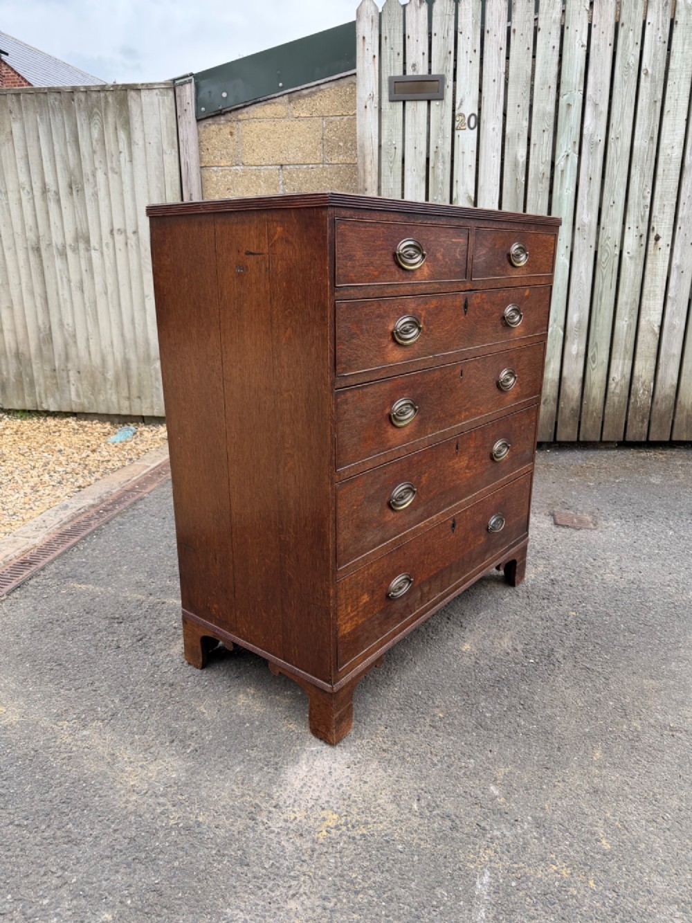 A Georgian oak chest of drawers featuring two short over three long graduated drawers with brass oval handles and bracket feet. View III
