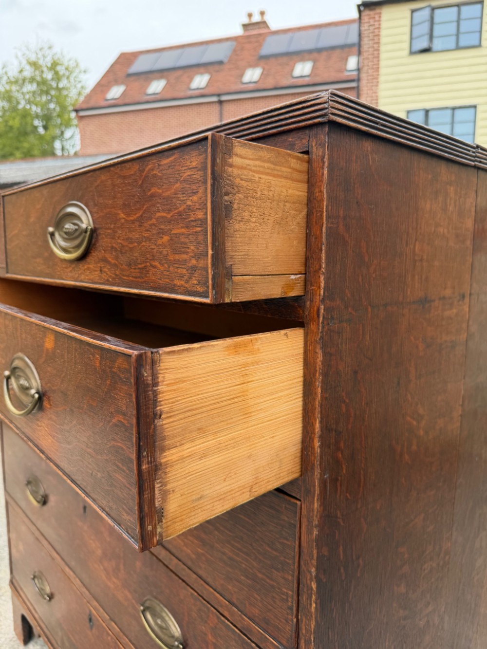 A Georgian oak chest of drawers featuring two short over three long graduated drawers with brass oval handles and bracket feet. View IV