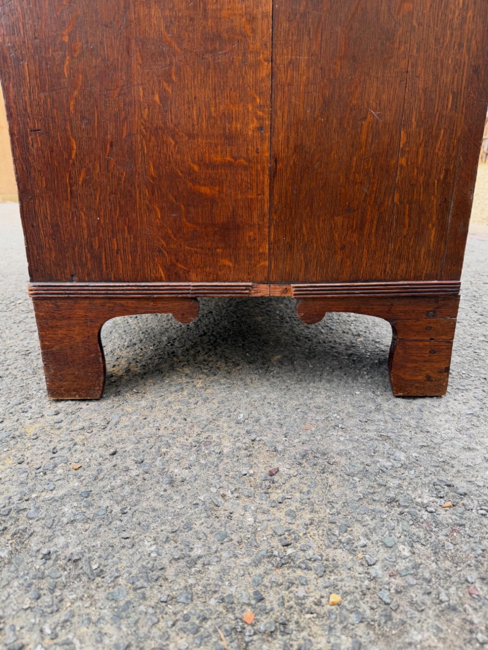 A Georgian oak chest of drawers featuring two short over three long graduated drawers with brass oval handles and bracket feet. View VII