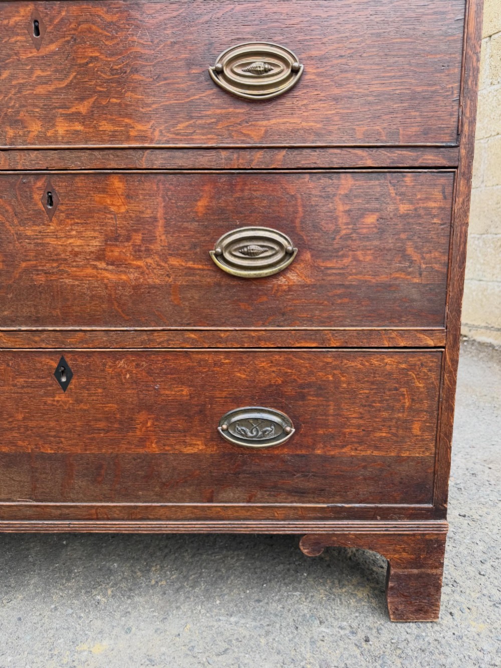 A Georgian oak chest of drawers featuring two short over three long graduated drawers with brass oval handles and bracket feet. View VIII