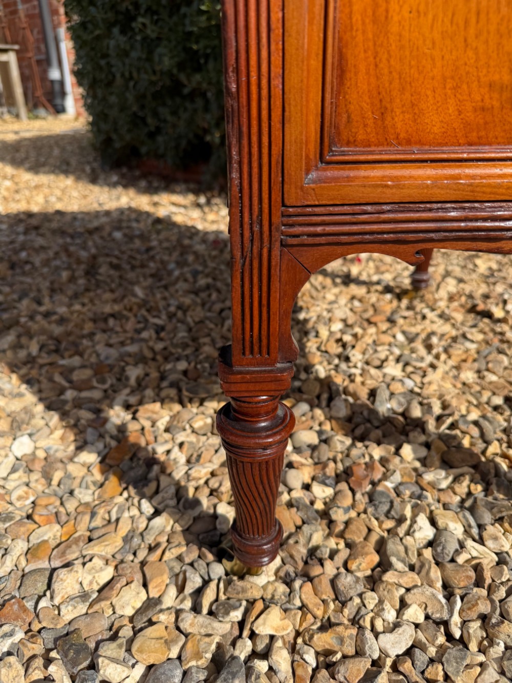 An antique walnut writing desk with a green leather inset top, brass drawer pulls, turned legs on castors, and built-in drawer pedestals. View VII