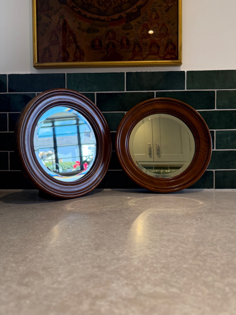 A pair of circular mirrors set in deep moulded warm brown walnut wood frames.