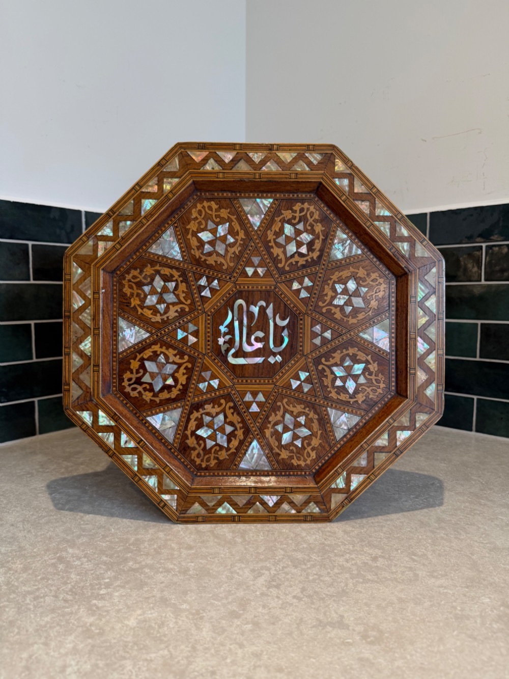 An octagonal wooden side table with intricate Moorish geometric marquetry, mother-of-pearl inlay, and Arabic calligraphy in the central medallion. View VI
