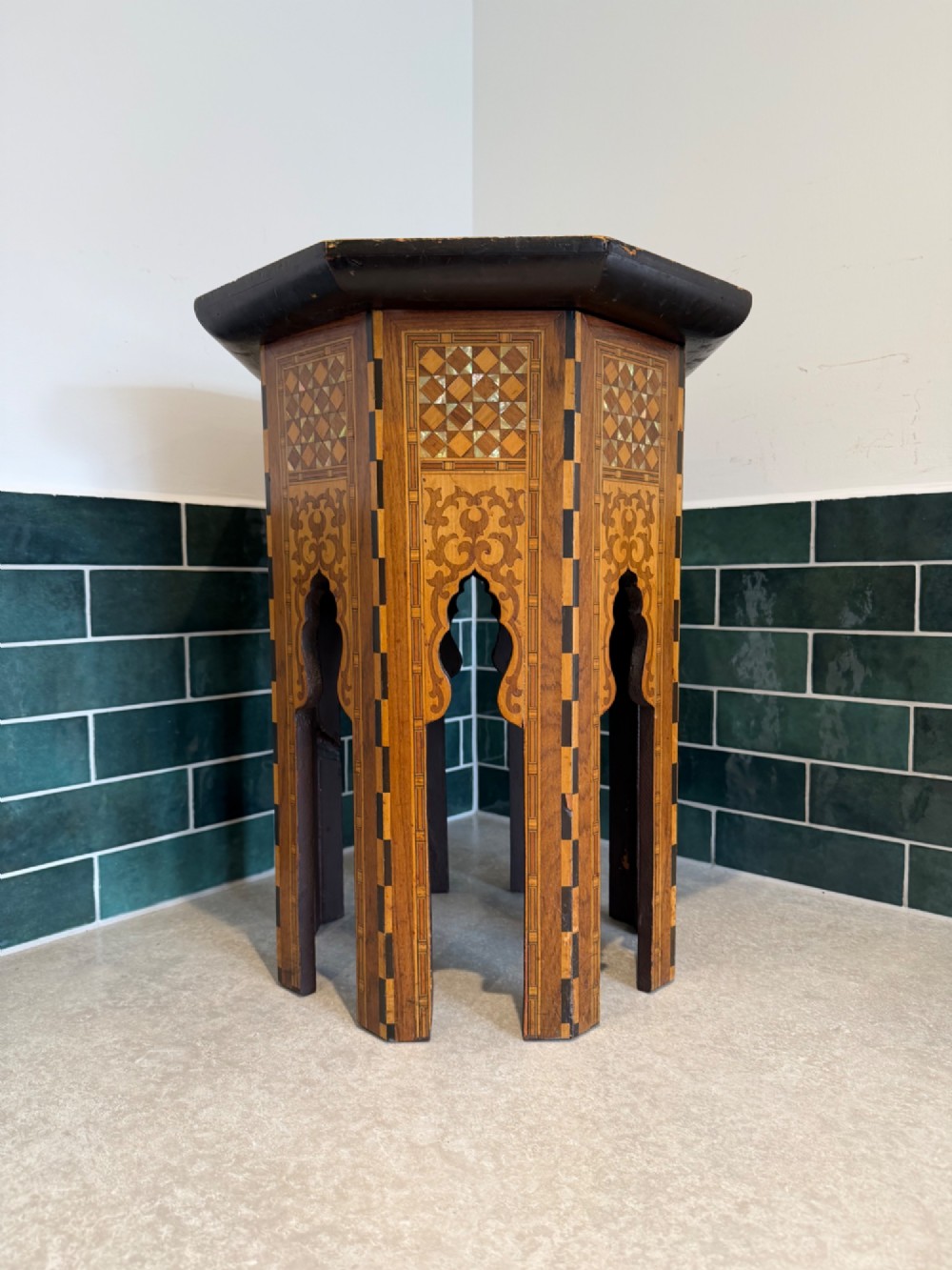 An octagonal wooden side table with intricate Moorish geometric marquetry, mother-of-pearl inlay, and Arabic calligraphy in the central medallion. View VII