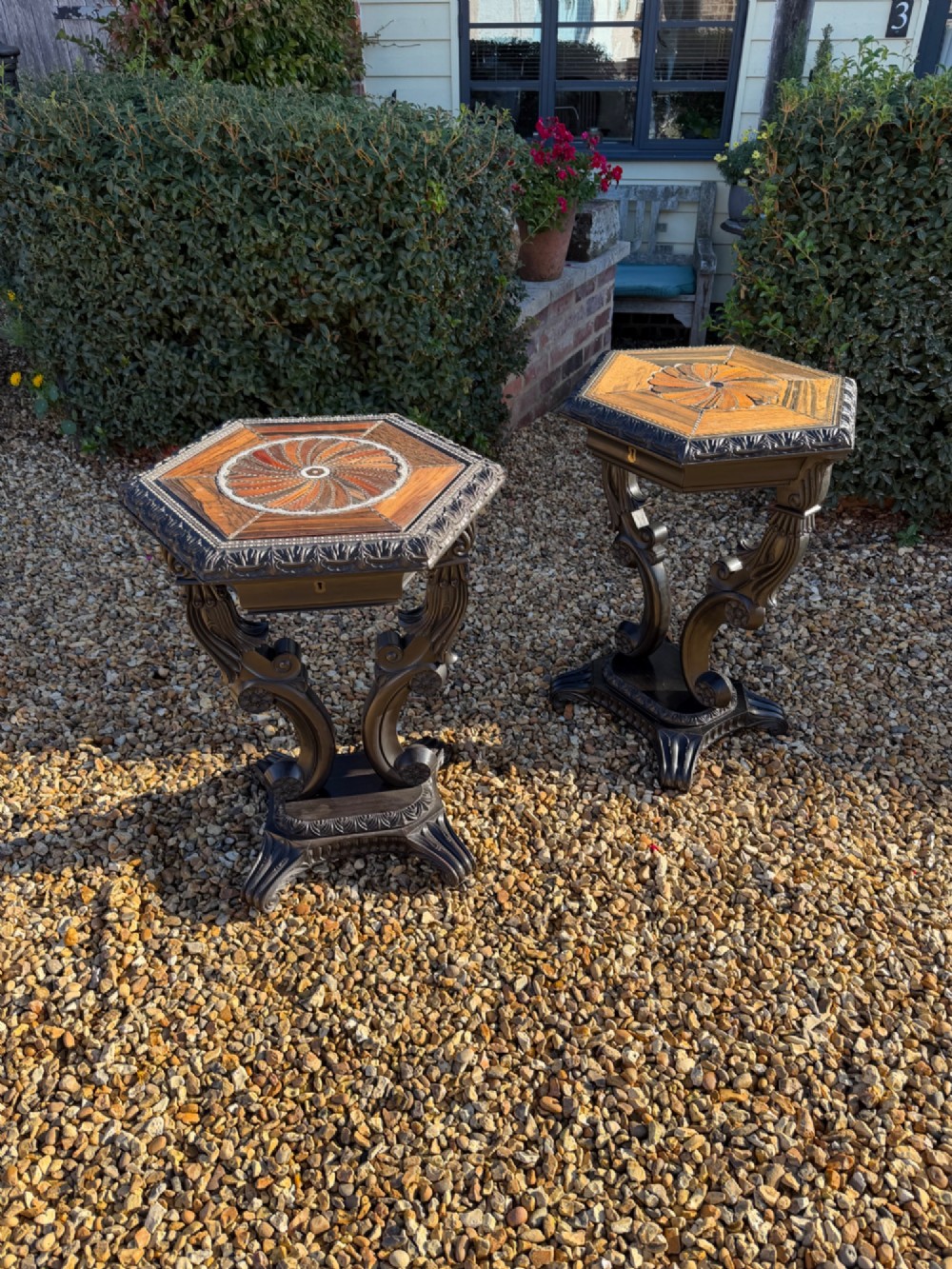 A pair of 19th-century Ceylonese ebony hexagonal occasional tables featuring inlaid geometric specimen wood tops and carved scroll legs.
