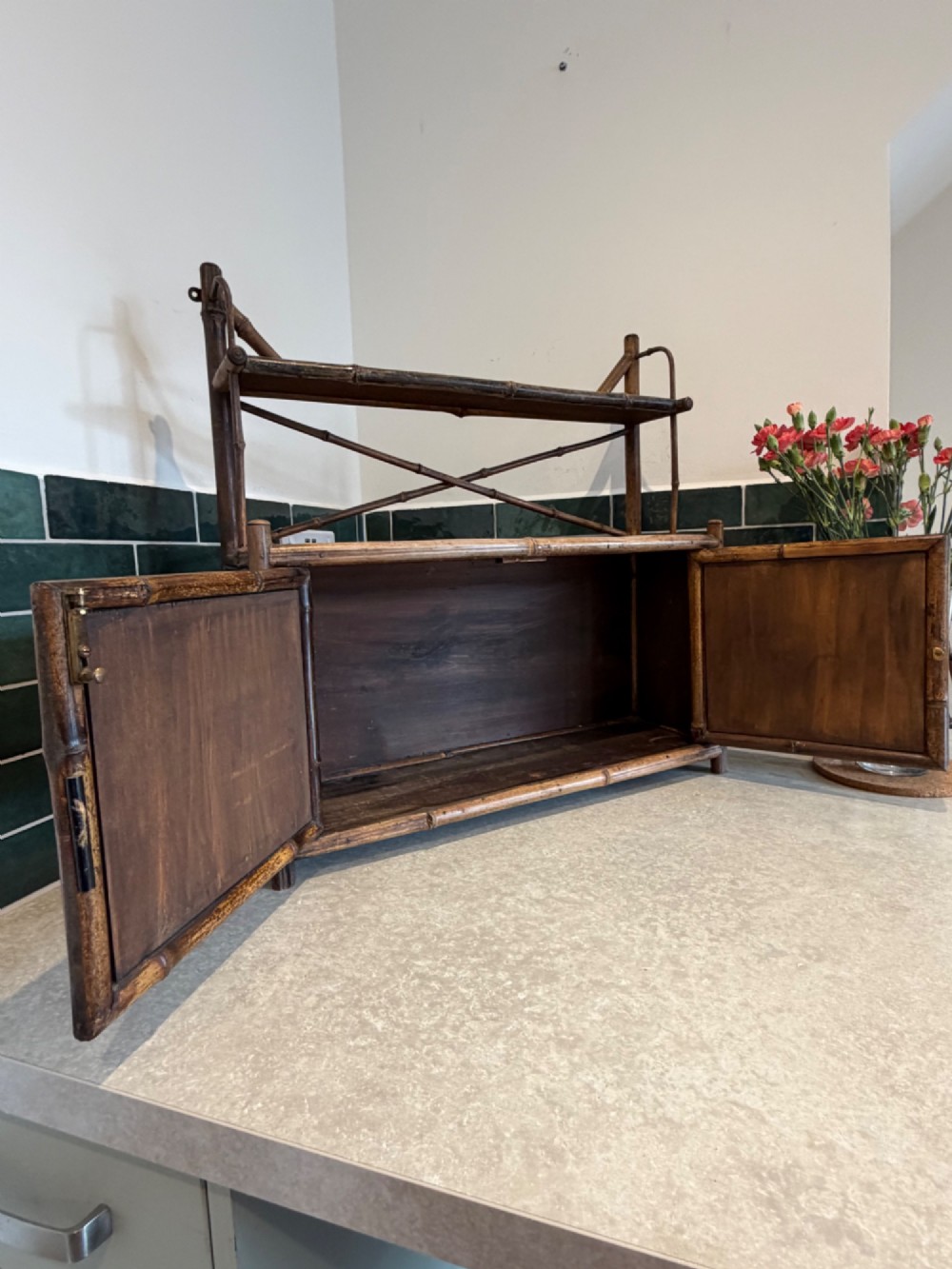 A Victorian bamboo and woven cane wall cupboard featuring two lower cabinet doors, an open upper display shelf, and an X-shaped cross support. View II