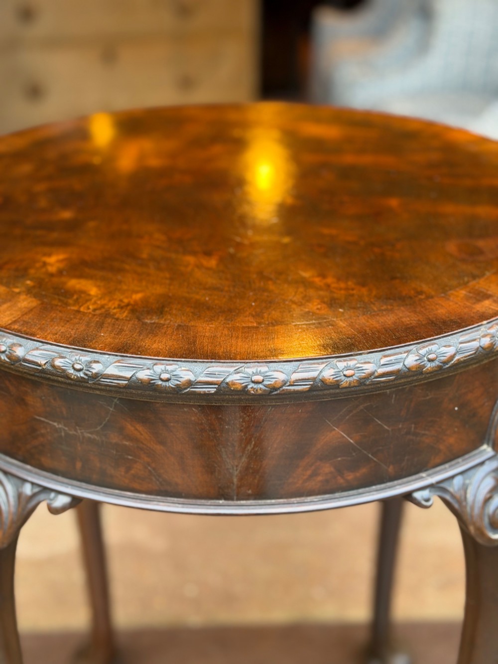 A circular mahogany occasional table featuring carved cabriole legs with pad feet and detailed knee carvings. View II