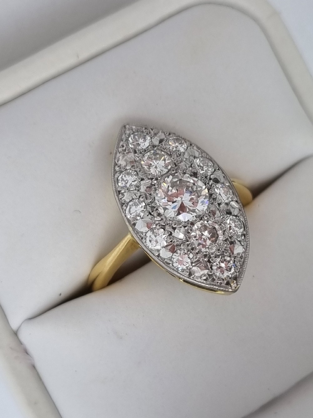 An antique navette-shaped cluster ring crafted in yellow gold with a platinum setting face set with multiple diamonds.
