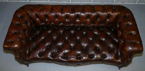 fig 2. A Victorian whisky brown leather Chesterfield sofa featuring a serpentine front, deep buttoned upholstery, brass stud detailing, and turned legs with brass castors.
