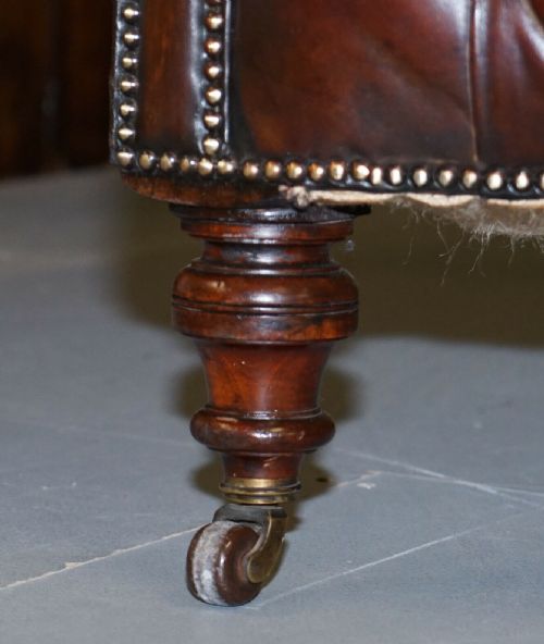 fig 3. A Victorian whisky brown leather Chesterfield sofa featuring a serpentine front, deep buttoned upholstery, brass stud detailing, and turned legs with brass castors.