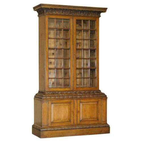 fig 2. A tall warm brown oak library bookcase featuring multi-paned glazed upper doors, intricate carved cornices, and a panelled two-door lower cabinet.
