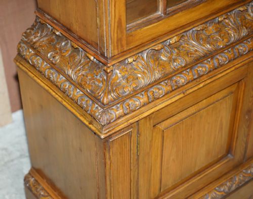 fig 4. A tall warm brown oak library bookcase featuring multi-paned glazed upper doors, intricate carved cornices, and a panelled two-door lower cabinet.
