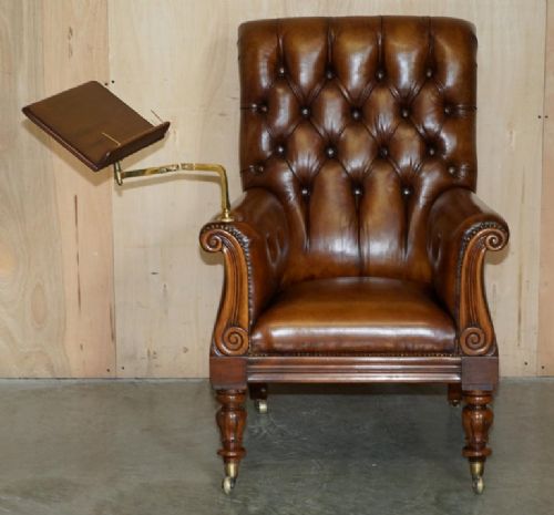 fig 1. A William IV brown leather Chesterfield armchair featuring deep buttoning, brass studding, turned legs on castors, and an attached swivel mahogany writing slope.
