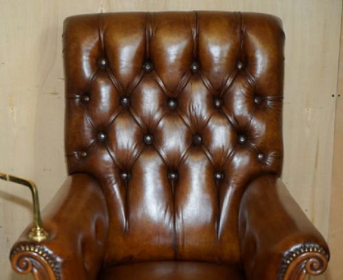 fig 2. A William IV brown leather Chesterfield armchair featuring deep buttoning, brass studding, turned legs on castors, and an attached swivel mahogany writing slope.