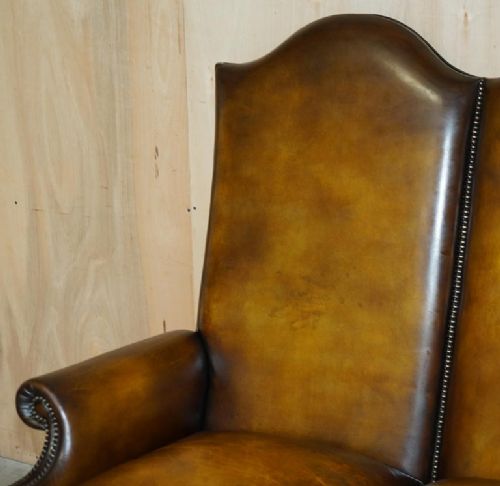 fig 2. A highback two-seater settee upholstered in warm brown leather with brass stud detailing and carved wooden cabriole legs.