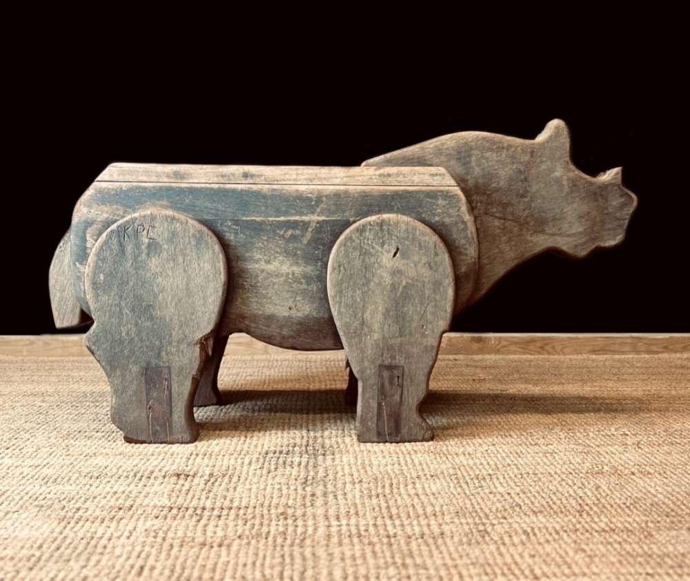 A carved solid oak bench shaped like a rhinoceros with a flat back seat and a dark timber finish.