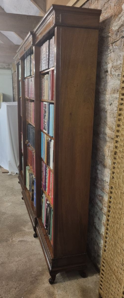 An Edwardian walnut breakfront open bookcase with three fitted sections, carved patera details, and fluted pilasters. View II