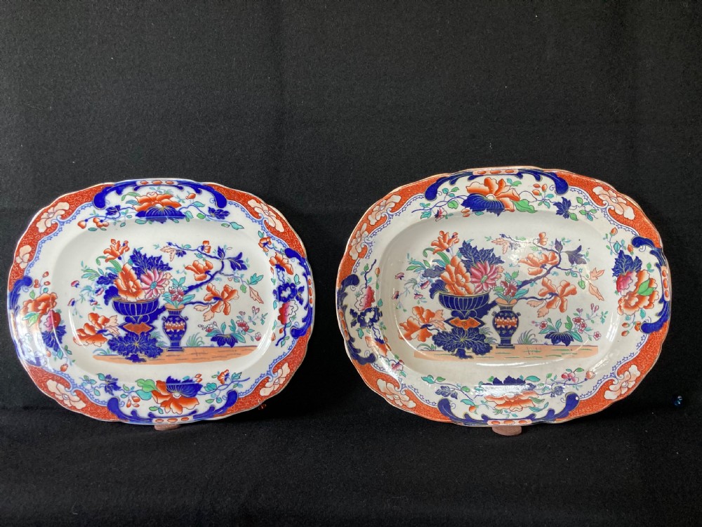 A pair of matching Victorian oval ironstone platters decorated with Imari style floral motifs in cobalt blue, terracotta, and gold detailing.