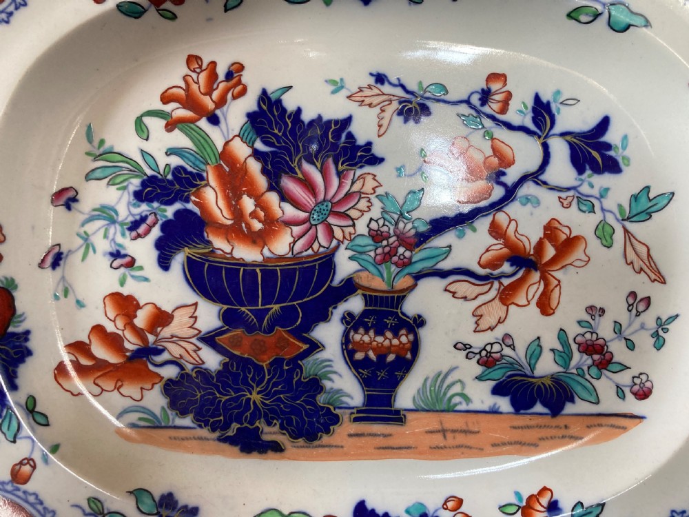 A pair of matching Victorian oval ironstone platters decorated with Imari style floral motifs in cobalt blue, terracotta, and gold detailing. View VI