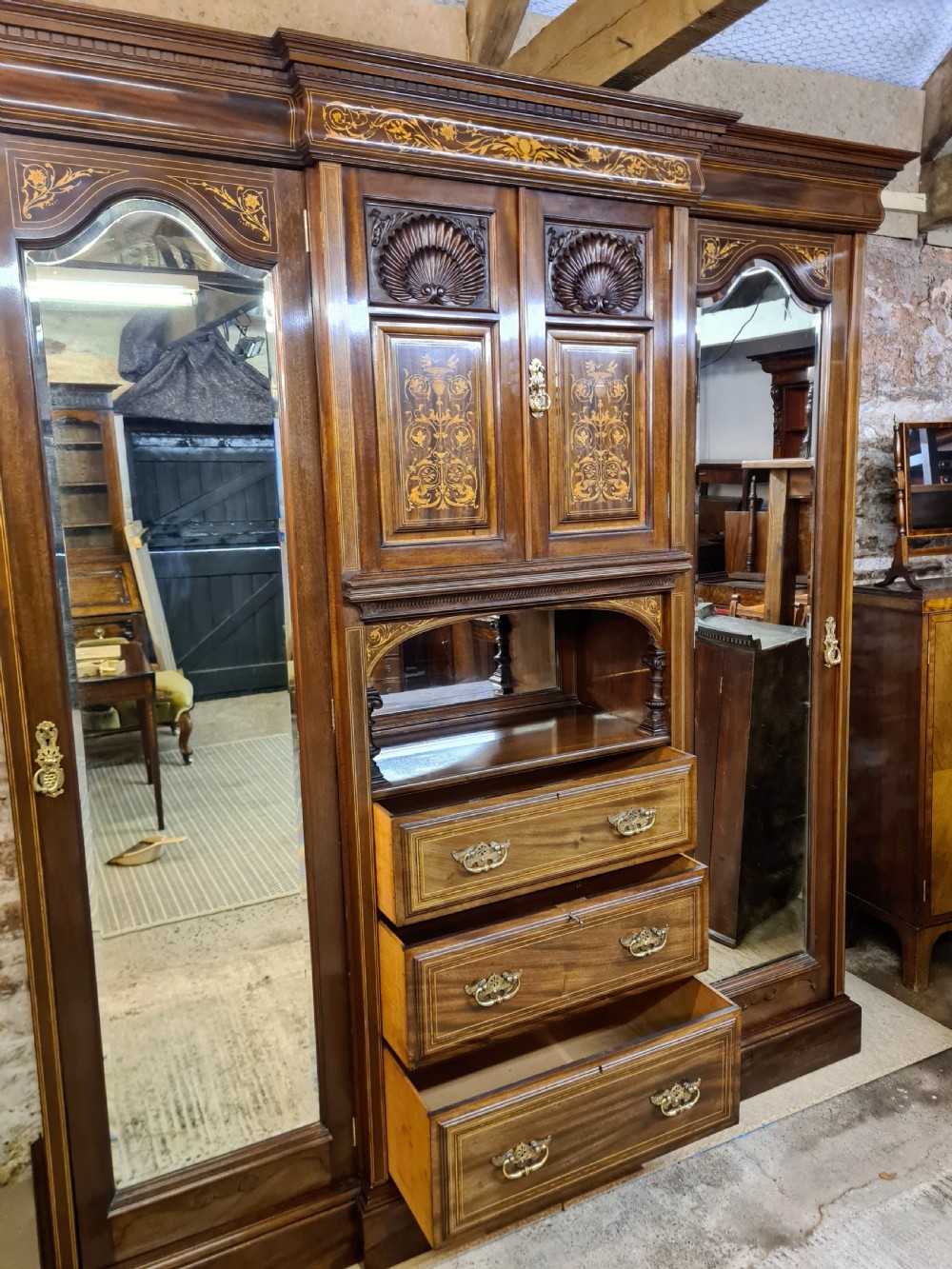 An Edwardian mahogany breakfront wardrobe with a central carved section, drawers, an open recessed shelf, and two full-length mirrored side doors. View III