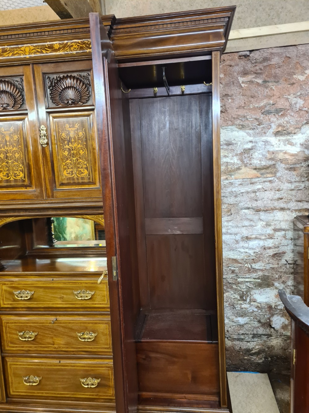 An Edwardian mahogany breakfront wardrobe with a central carved section, drawers, an open recessed shelf, and two full-length mirrored side doors. View V
