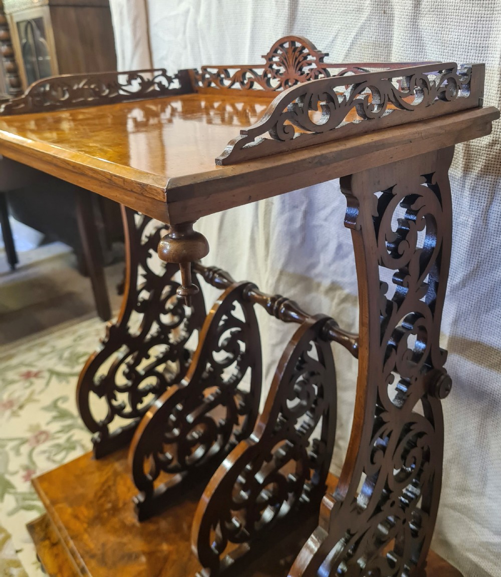 Victorian burr walnut Canterbury featuring intricate pierced fretwork dividers, an upper shelf with carved gallery, and turned legs on brass castors. View VII