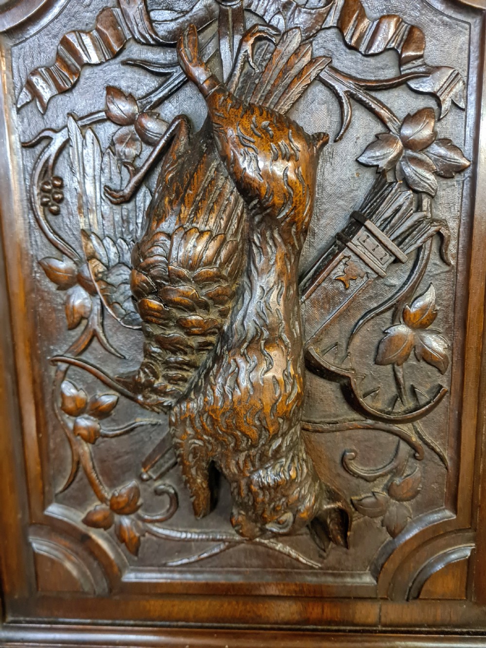 A pair of dark oak timber panels featuring high-relief relief carvings of game birds, a rabbit, ribbons, and hunting equipment. View IV