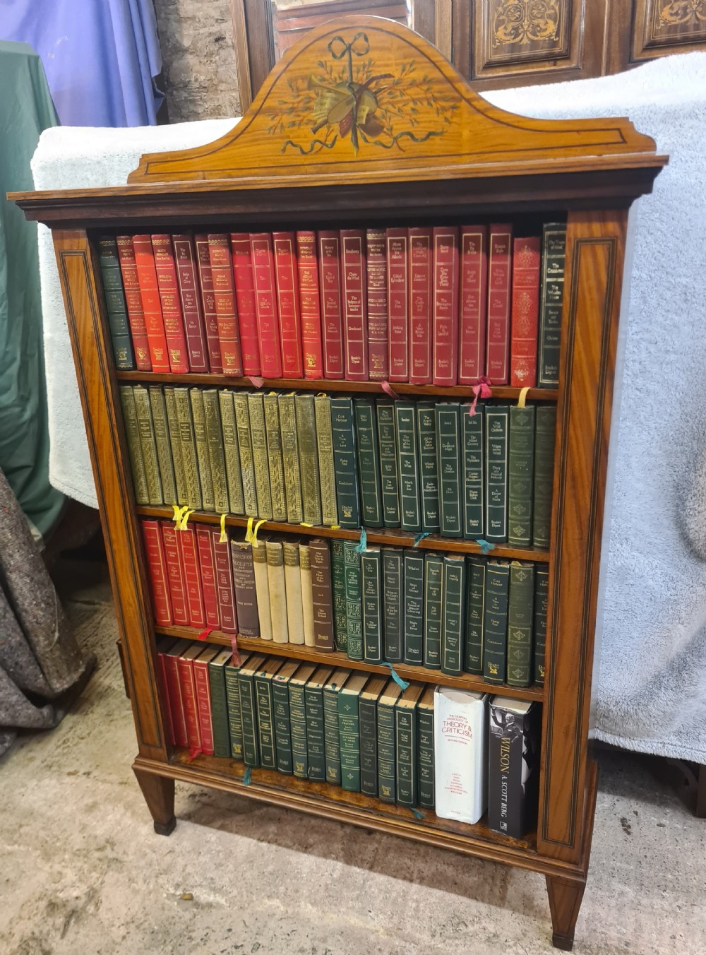 A Victorian satinwood open bookcase featuring four tiered shelves and an arched pediment decorated with marquetry foliage and musical instruments. View II