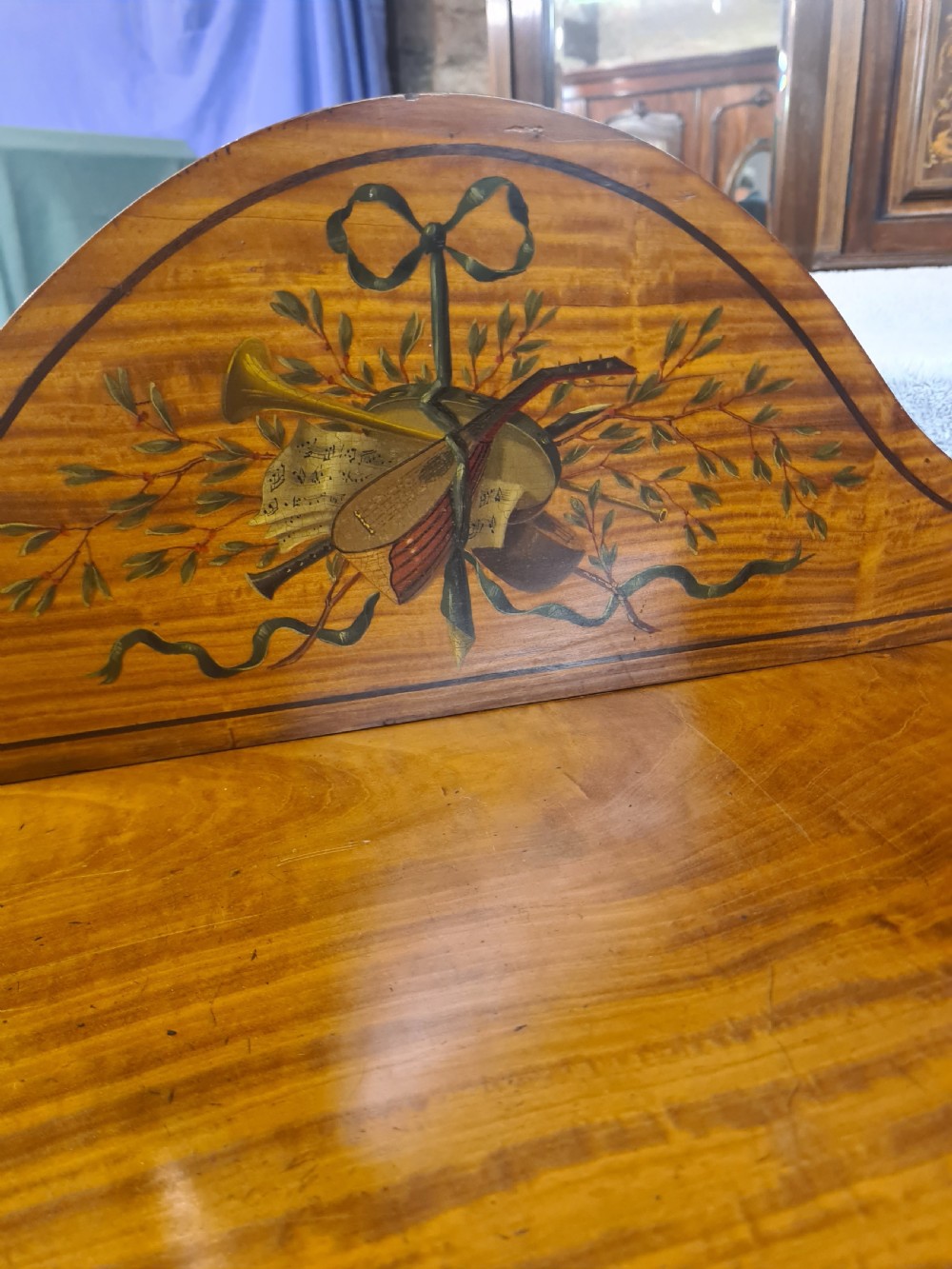 A Victorian satinwood open bookcase featuring four tiered shelves and an arched pediment decorated with marquetry foliage and musical instruments. View III