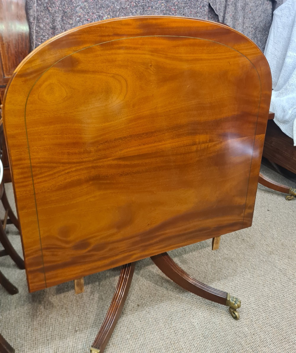 A polished warm brown mahogany dining table featuring fine brass inlay stringing around the perimeter with an inserted central leaf. View VIII