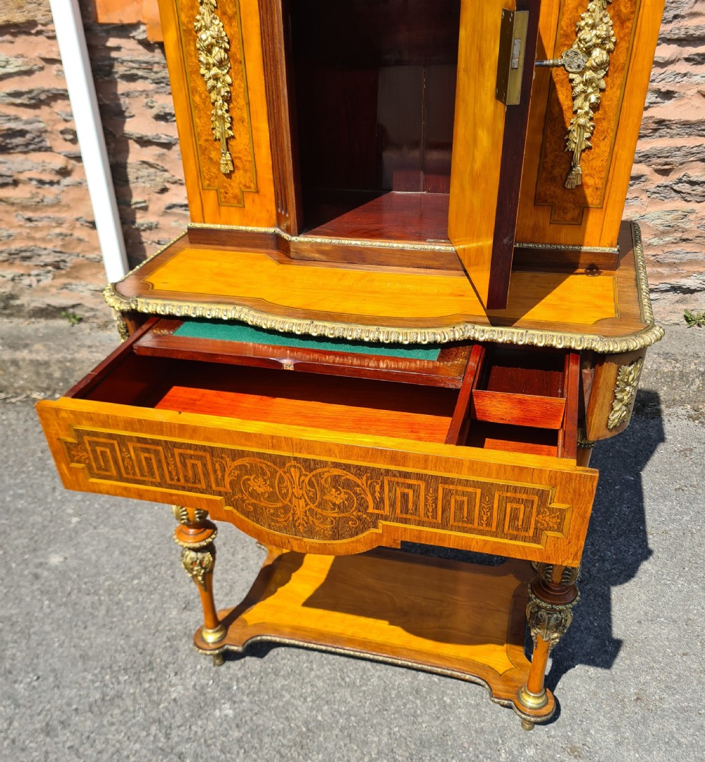 A French satinwood and amboyna bonheur de jour desk featuring ornate gilt-bronze mounts, an inlaid Greek key drawer pattern, and a central cabinet door set with a hand-painted porcelain portrait plaque. View IX
